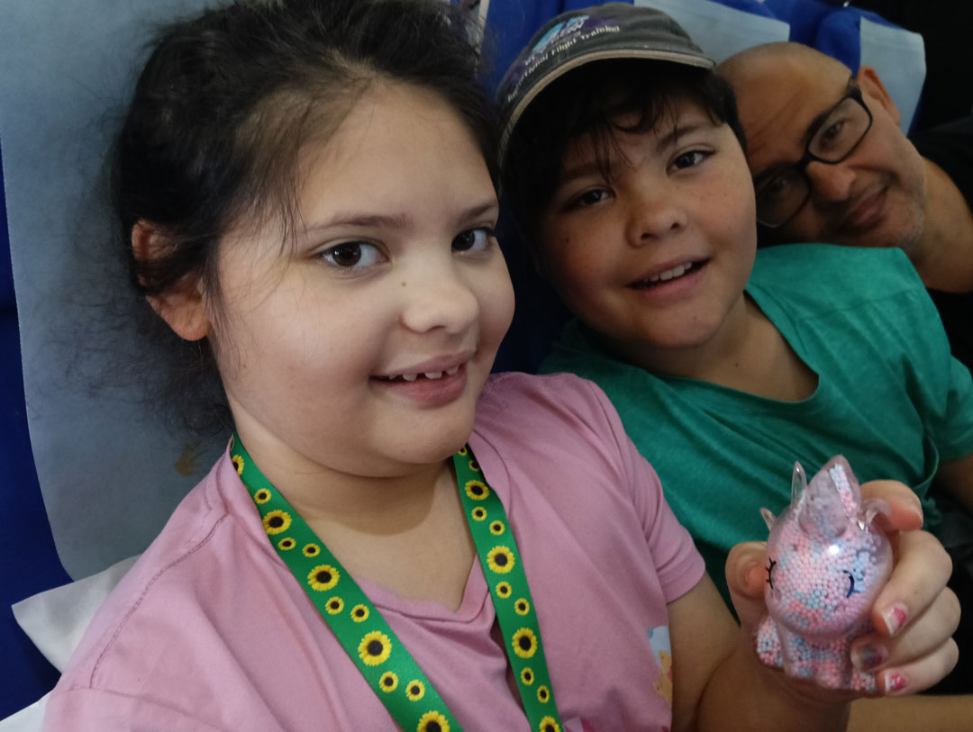 Family enjoying a flight together — two children smiling with their father while traveling, highlighting accessible and family-friendly air travel experiences.