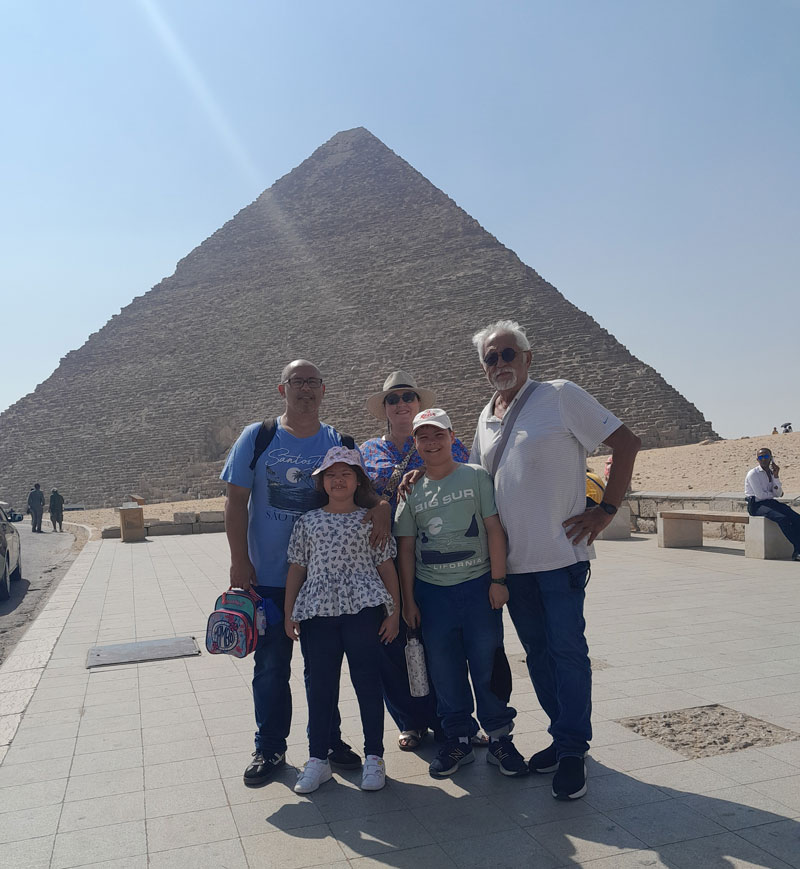 Family of four with a grandfather standing infront of Khufu pyramid in Giza, Egypt