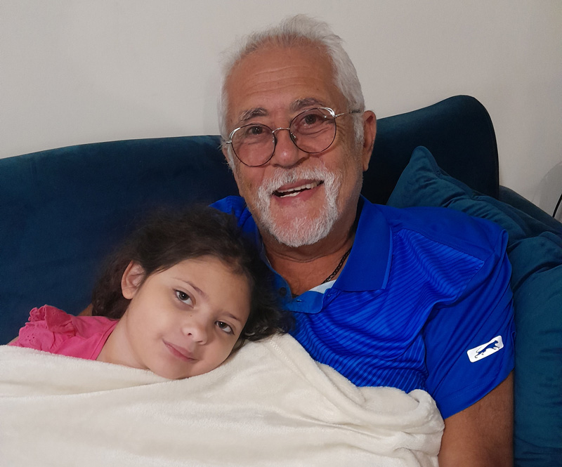 A grandfather and his granddaughter snuggled together on the couch