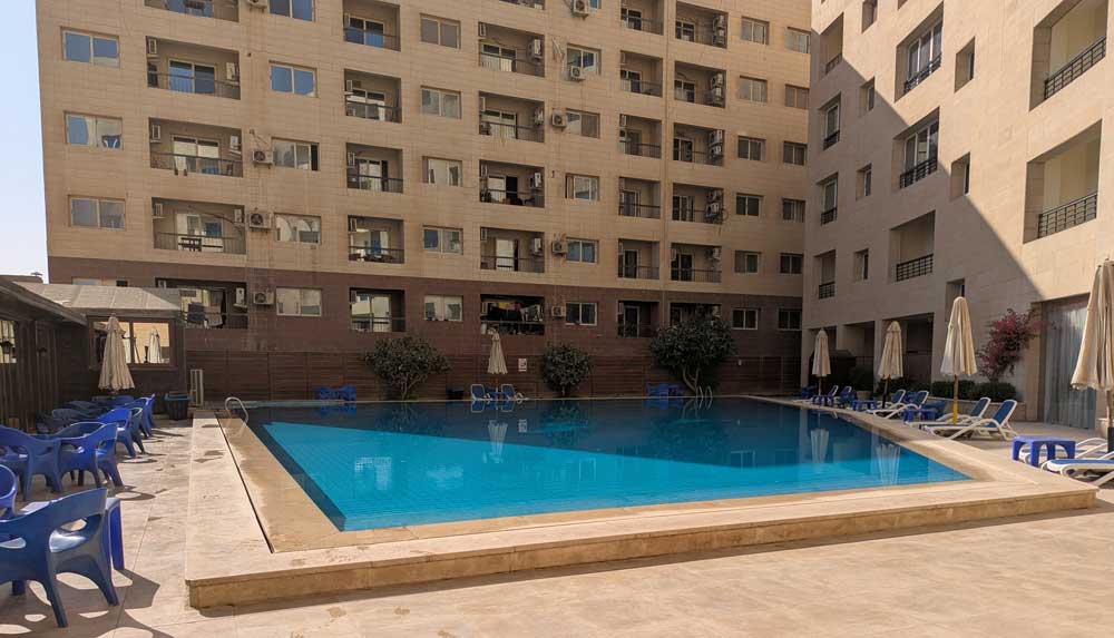 Clear, blue water in a pool in the foreground with a high rise hotel in the background