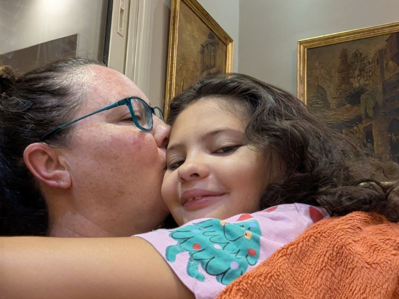 Woman kissing girl as they snuggle.