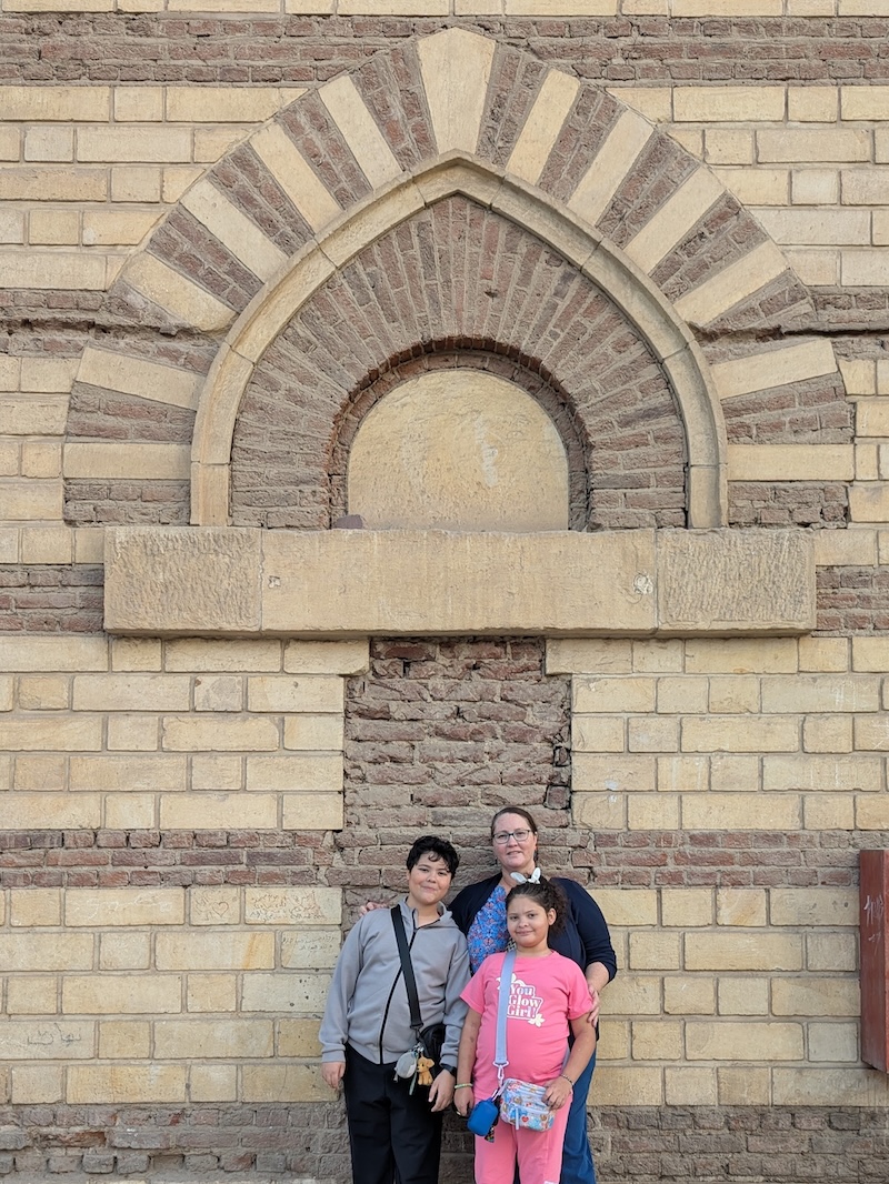 Mother, son and daughter standing in front of an arch and striped designed architecture