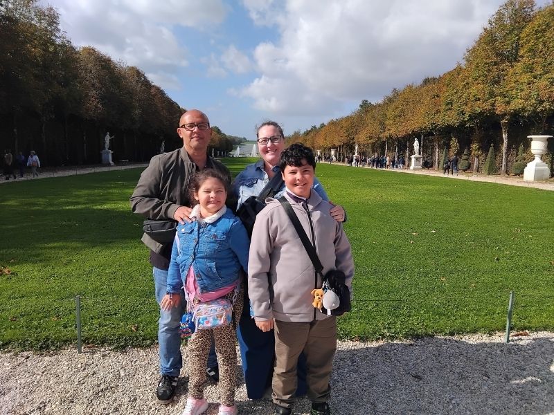 Mother, father, daughter and son standing in front of the gardens of Versailles